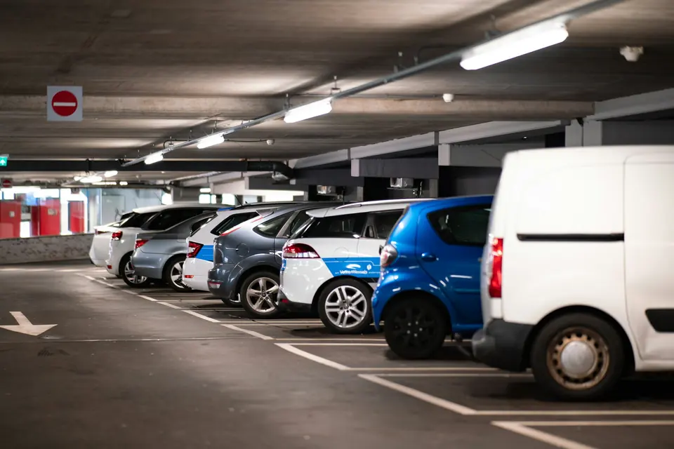Biler og en varebil parkert på rekke i et parkeringshus
