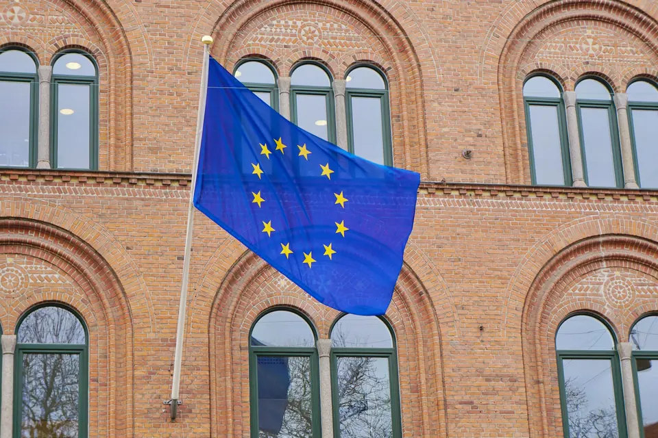 EU-flagget vaier foran en fasade i rød murstein med buede vinduer